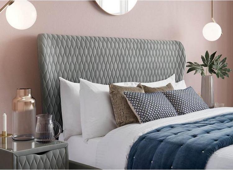 Grey velvet bed frame, styled with blue and white bedding against a pink wall