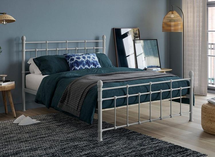 A grey metal bed frame, styled in a neutral blue bedroom