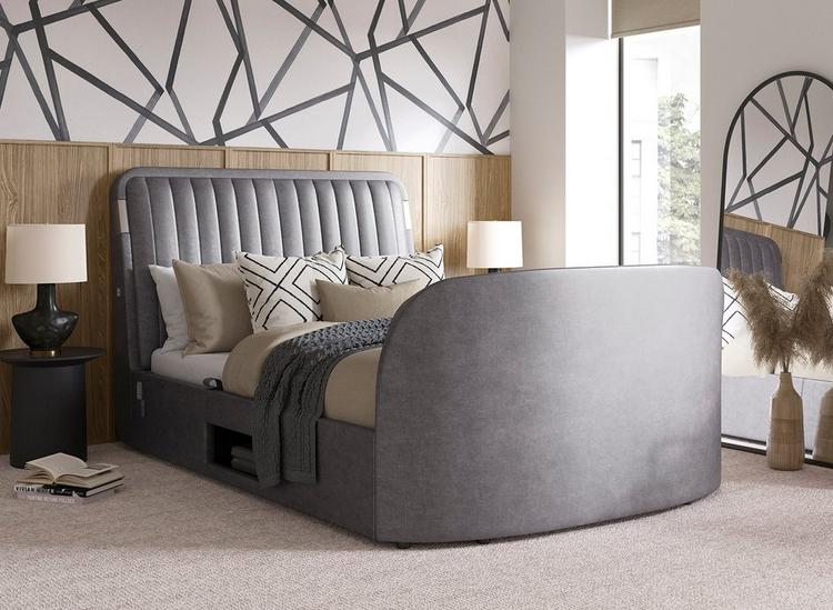 Grey velvet-touch TV bed with fluted headboard, styled in a bedroom with wall panelling and statement wallpaper.