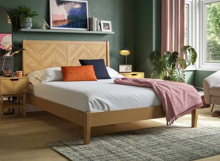 Wooden parquet-inspired bed frame, styled against a deep green wall with floating shelves.