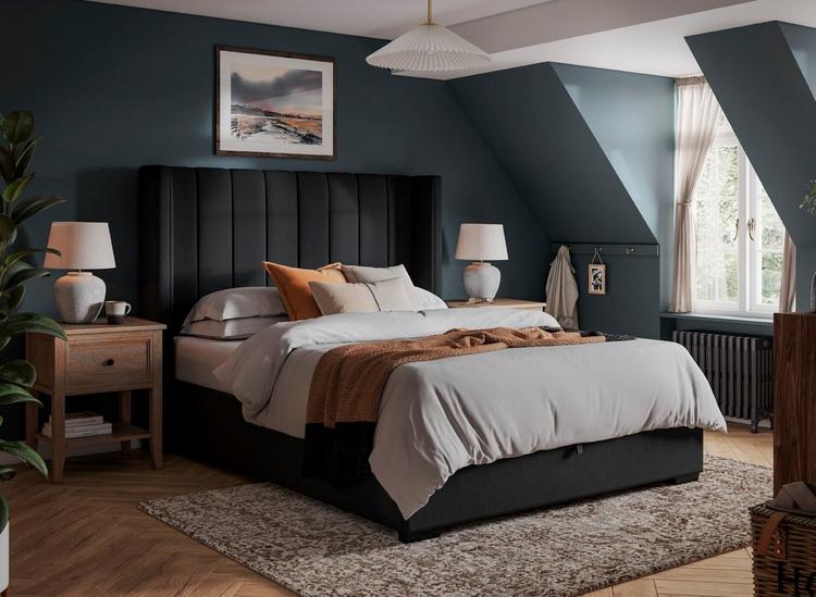 A black velvet bed frame with high headboard, styled in a neutral blue bedroom.