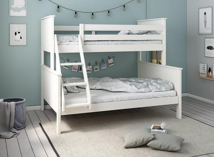 A kids triple bunk bed finished in white wood, styled in a neutral blue kids room.