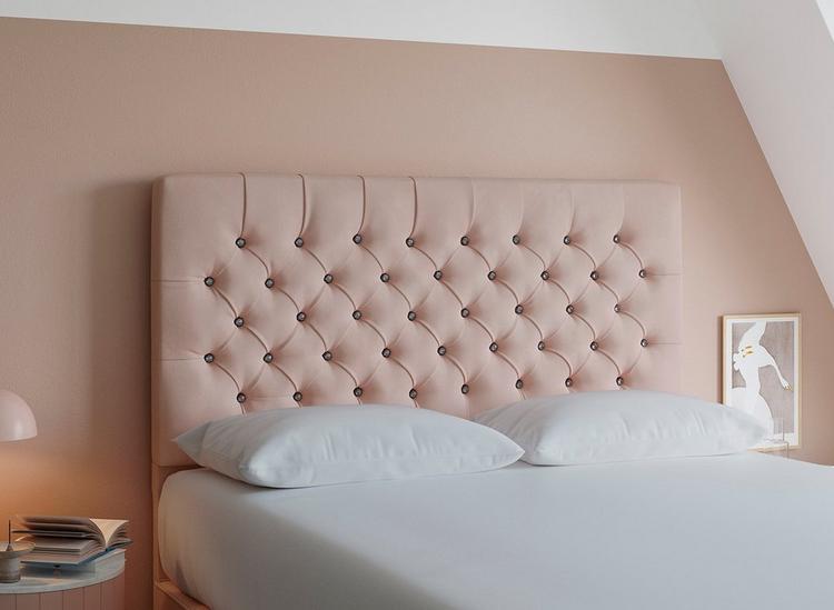 A pink velvet double headboard with diamante button detailing, set against a pink painted wall.