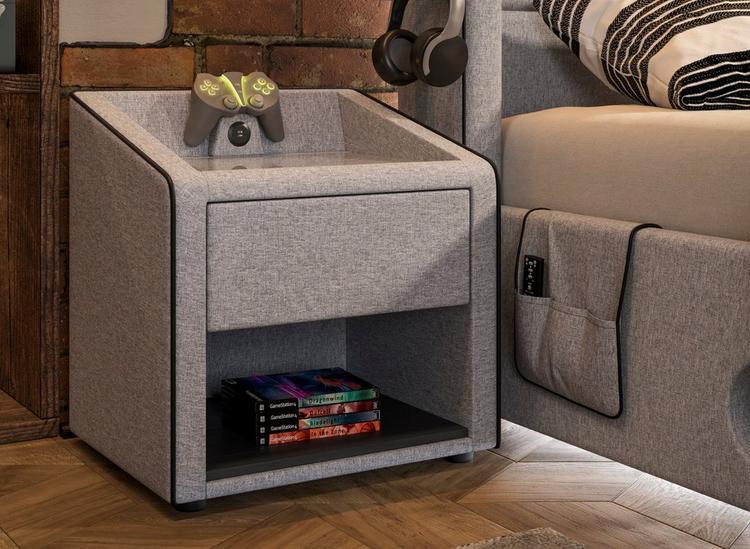Modern grey upholstered beside, with USB charging ports and controller stand, styled next to a gaming bed.