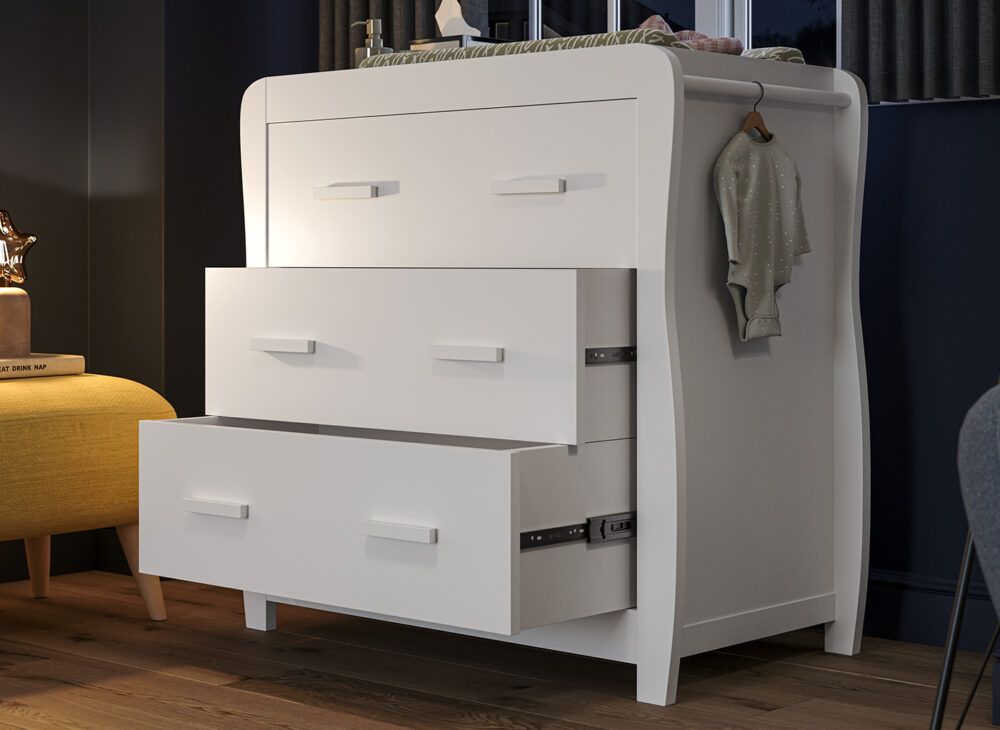 A white 2-in-1 chest and changing station, styled in a dark and cosy nursery with soft lamp light.