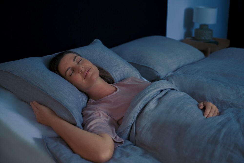 A motion-enabled TEMPUR Smart Bed, showing a woman sleeping comfortably in her perfect sleep position