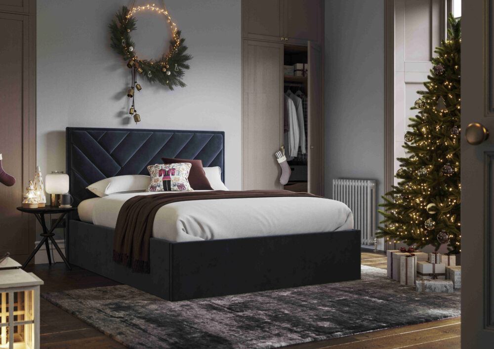 Navy velvet ottoman bed frame, styled in a Christmas-themed room with festive decor and Christmas tree