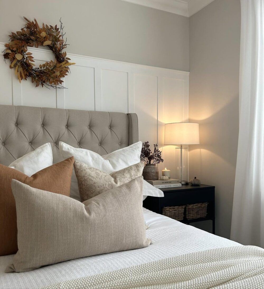 image of a bed with a taupe chesterfield buttoned headboard with scatter cusions on top of white and grey bedding