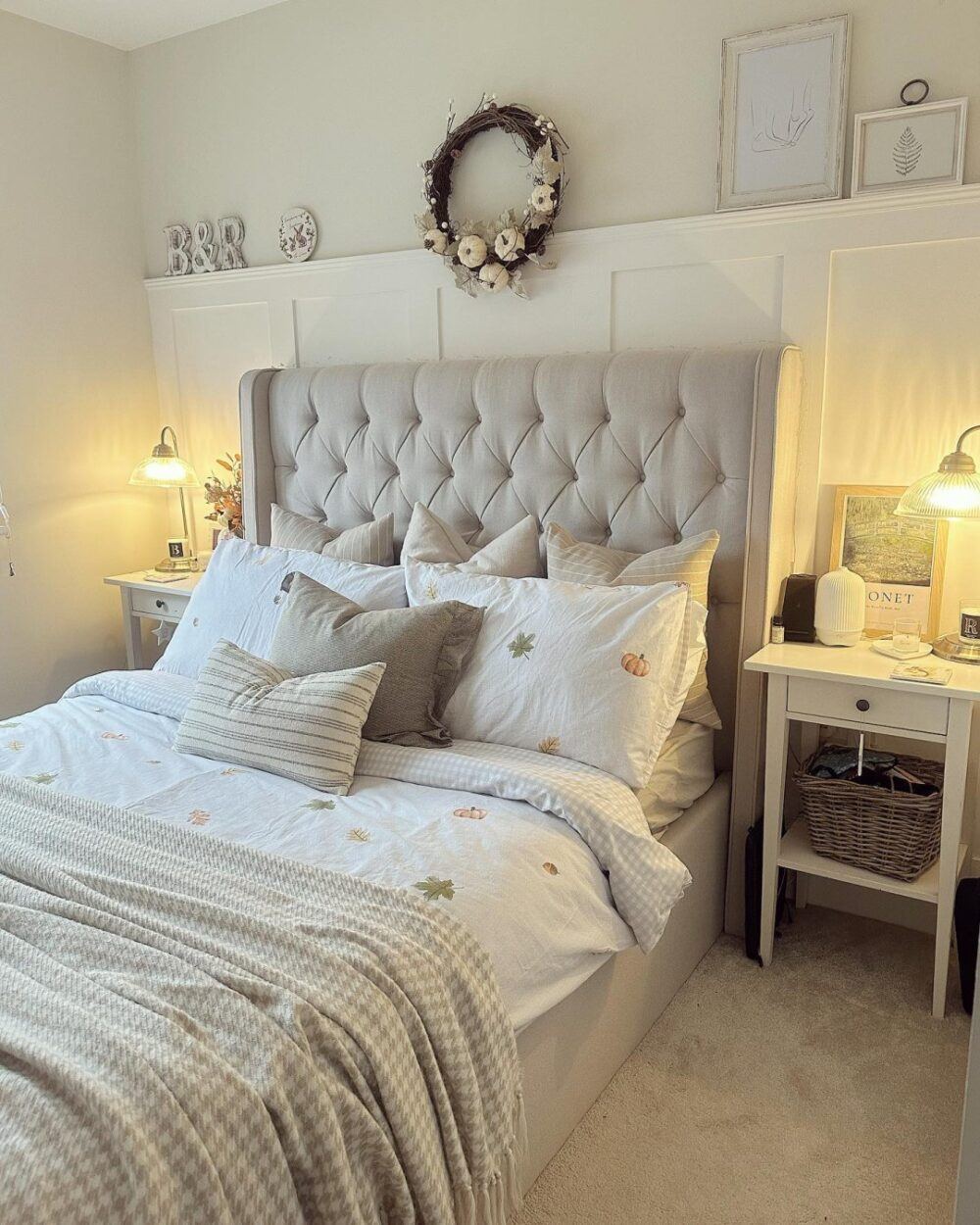 A neutral upholstered bed frame with high buttoned headboard, styled in a neutral bedroom