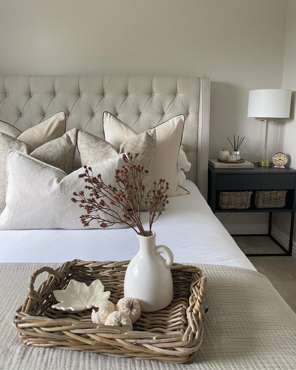 Beige buttoned bed frame, styled with flowers and woven accents.