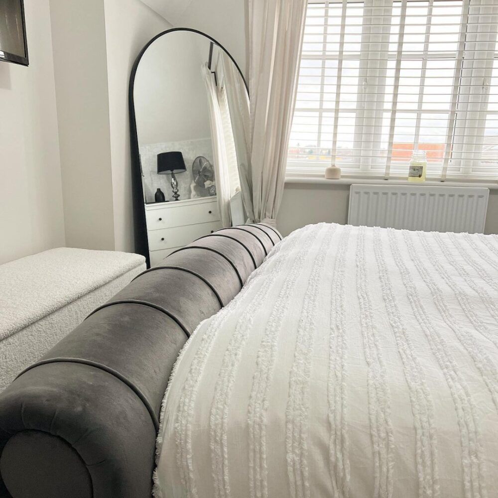 Grey velvet bed, styled in a white room with large mirror