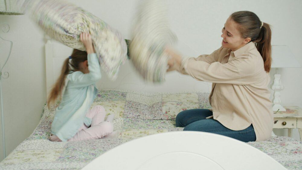 Mother and daughter having a pillow fight in the bedroom