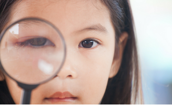 Young girl looking through a magnifying glass