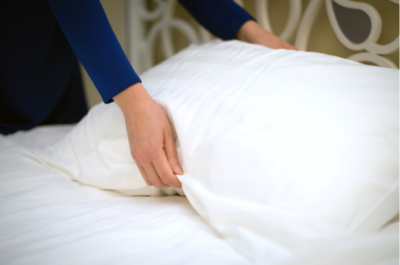 Fluffing pillow on bed