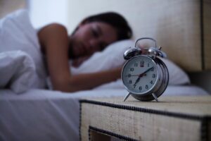 Woman sleeping in bed with alarm clock