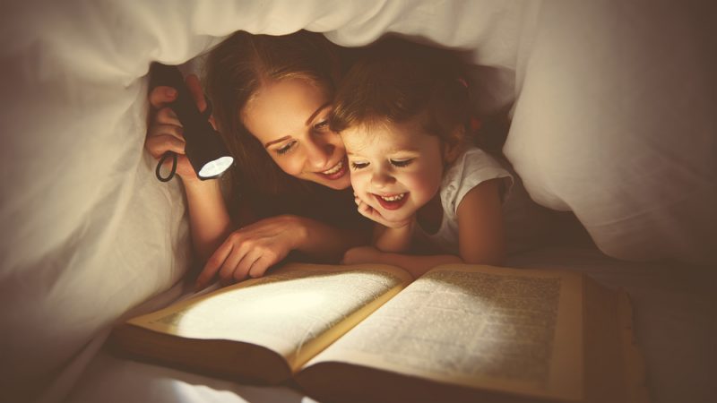 Mother and child reading under duvet