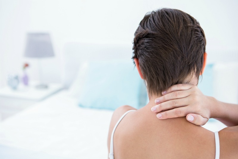 A woman suffering from neck pain in bed