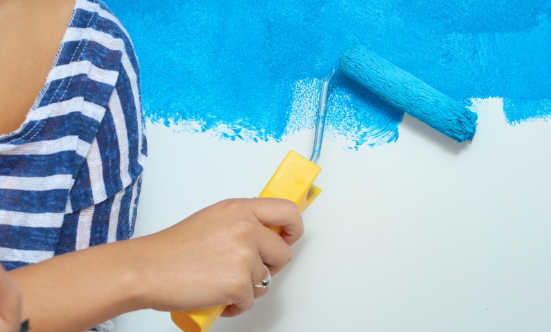 image of a woman painting a wall