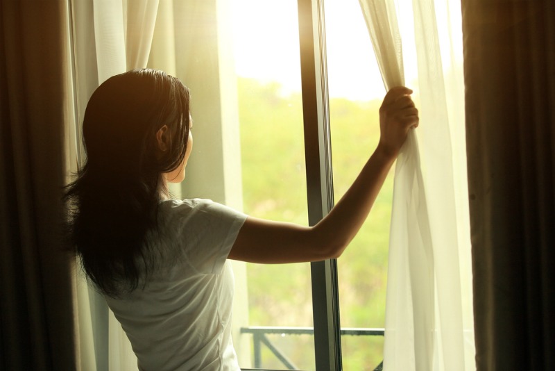 An image of a woman opening curtains