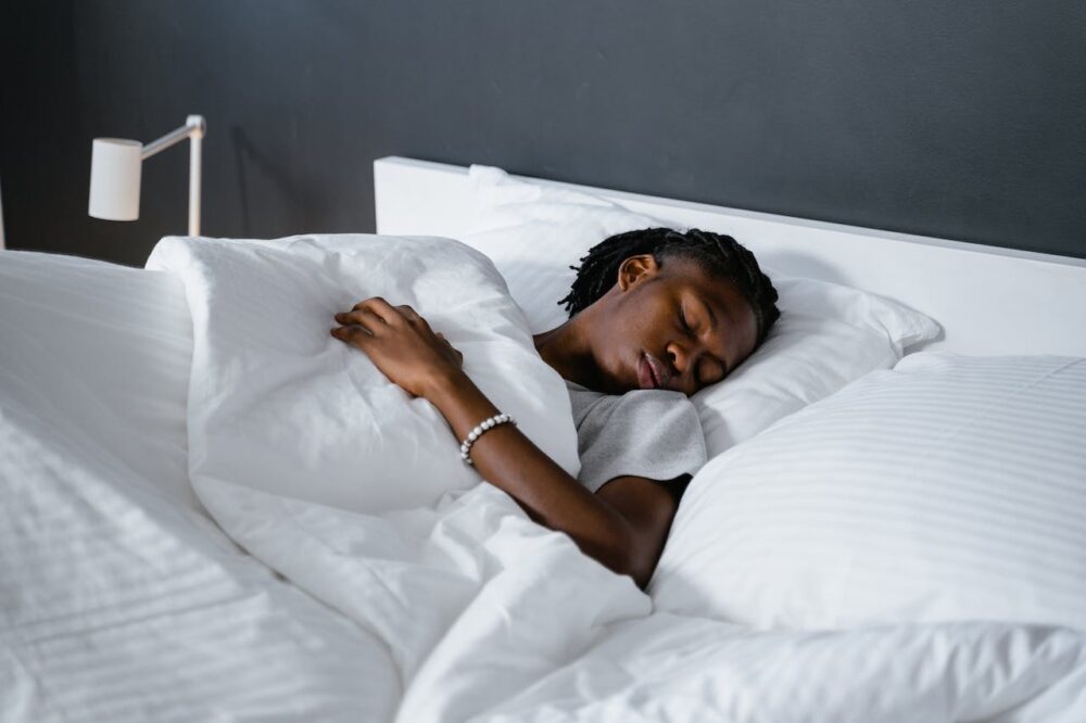 Young adult sleeping in white bedding