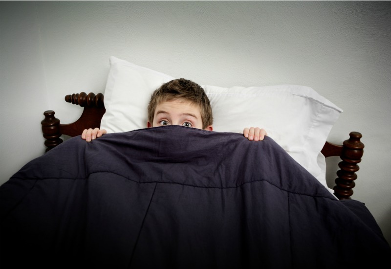 Garçon au lit tenant des couvertures