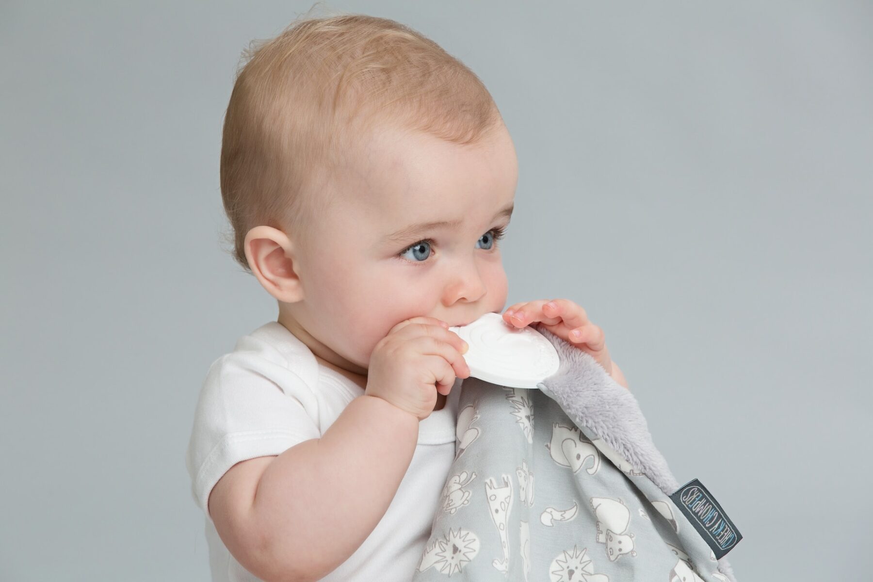 Cute baby chewing on teething blanket