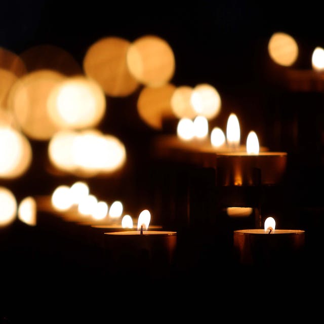 Image of several lighted candles against a dark black background