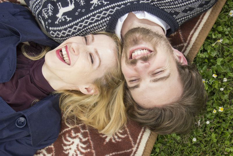 Happy couple lying on grass laughing