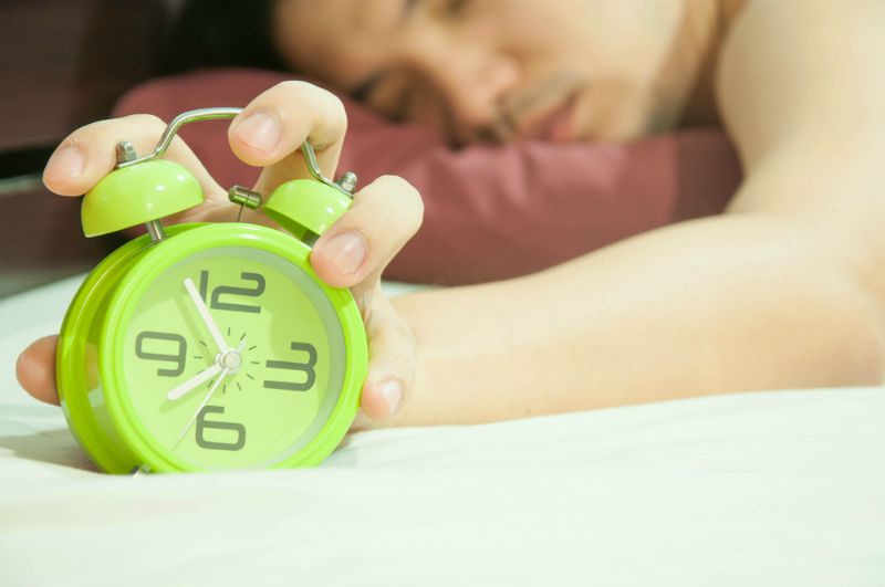 Man stopping green alarm clock