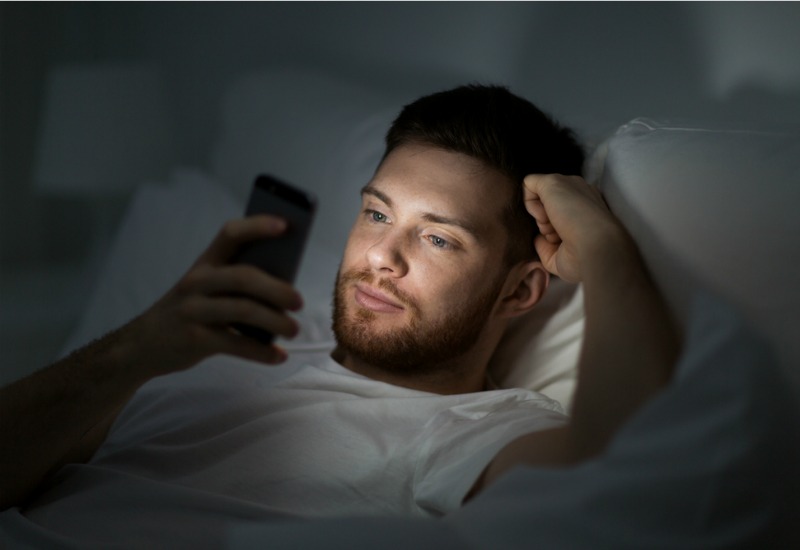 Man using smartphone in bed
