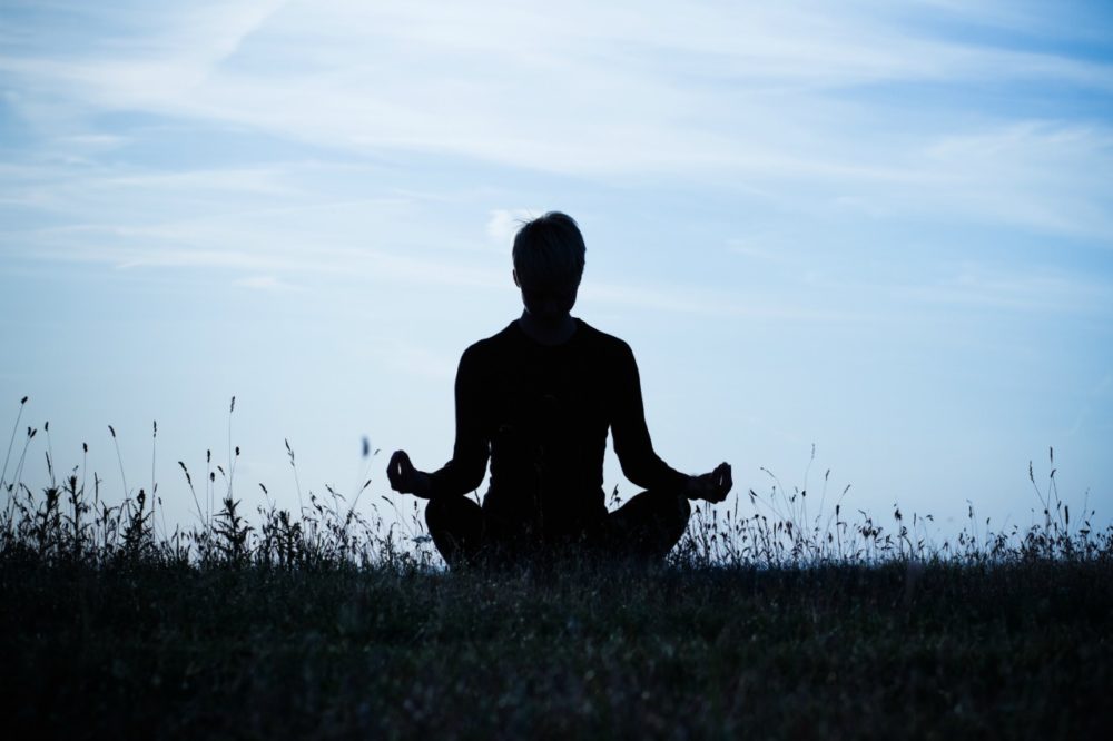 A man sat in a meadow doing meditation