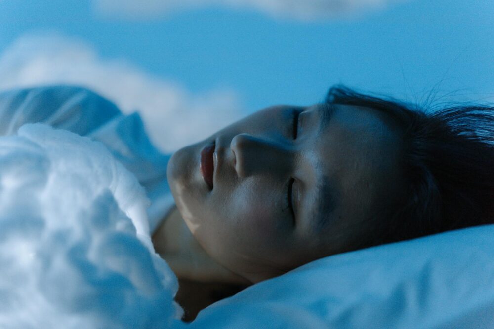 A tranquil scene of a woman sleeping comfortably on a white pillow, evoking peace.