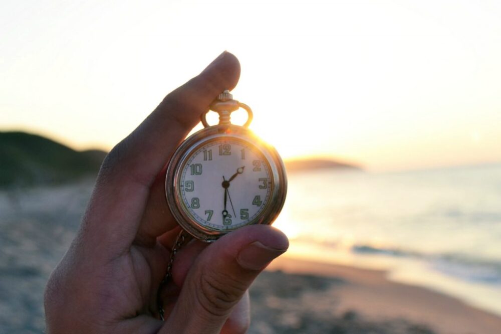 pocket watch being held with sunset background