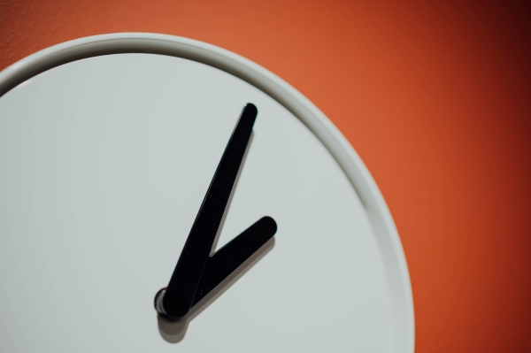 A white clock against an orange wall