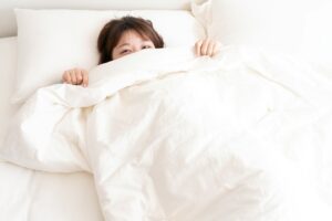 Woman hiding behind duvet