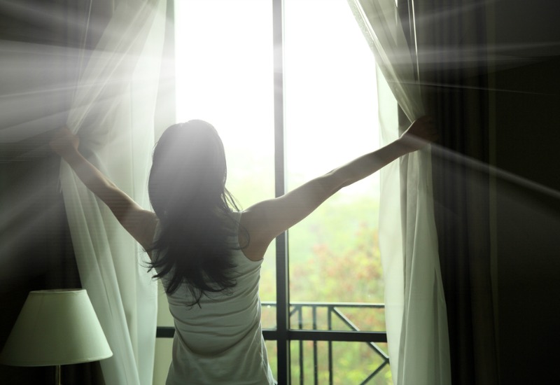 Woman opening curtains